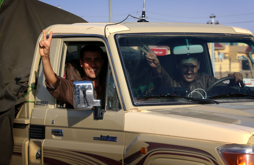 Kurdish peshmerga troops flash the V-sign of victory as they drive through Arbil after dozens of fighters left a base in northern Iraq on October 28, 2014 on their way to the battleground Syrian town of Kobane.