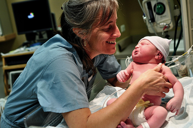 A midwife holds a newborn after delivery.