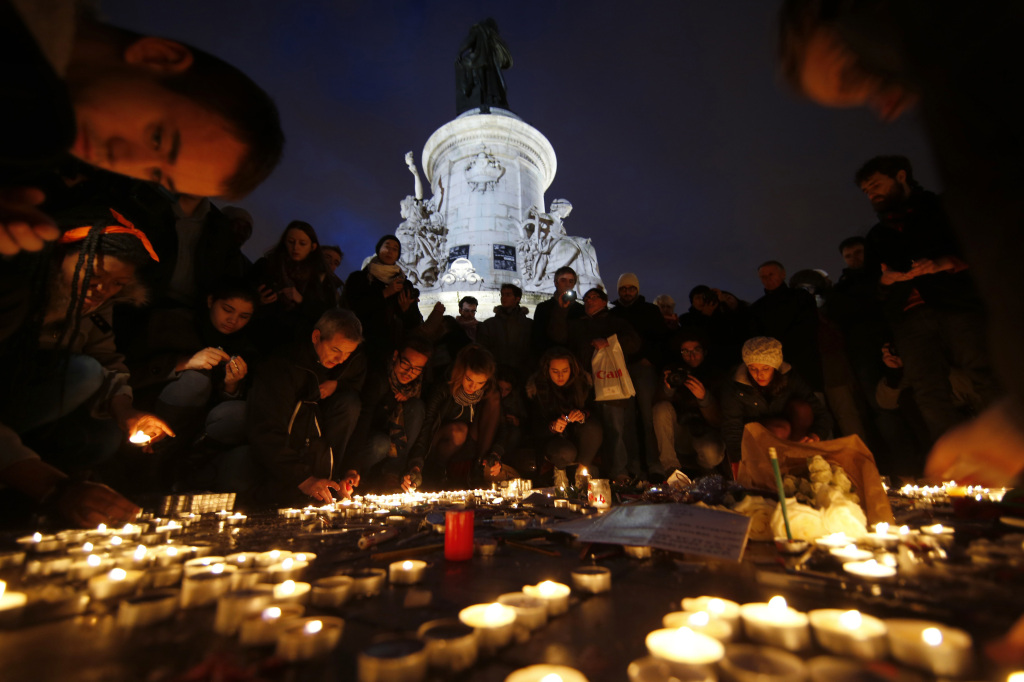 People lay candles during a gathering on the Place de Republique (Republic square) in Paris, on January 8, 2015, as a tribute to the 12 people killed by two gunmen at the French weekly newspaper Charlie Hebdo's editorial office. 
