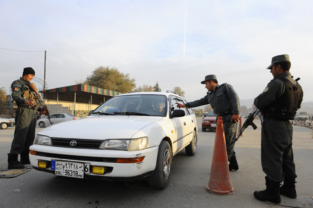 Afghan policemen search a car at a checkpoint in Kabul on November 18, 2013. 
