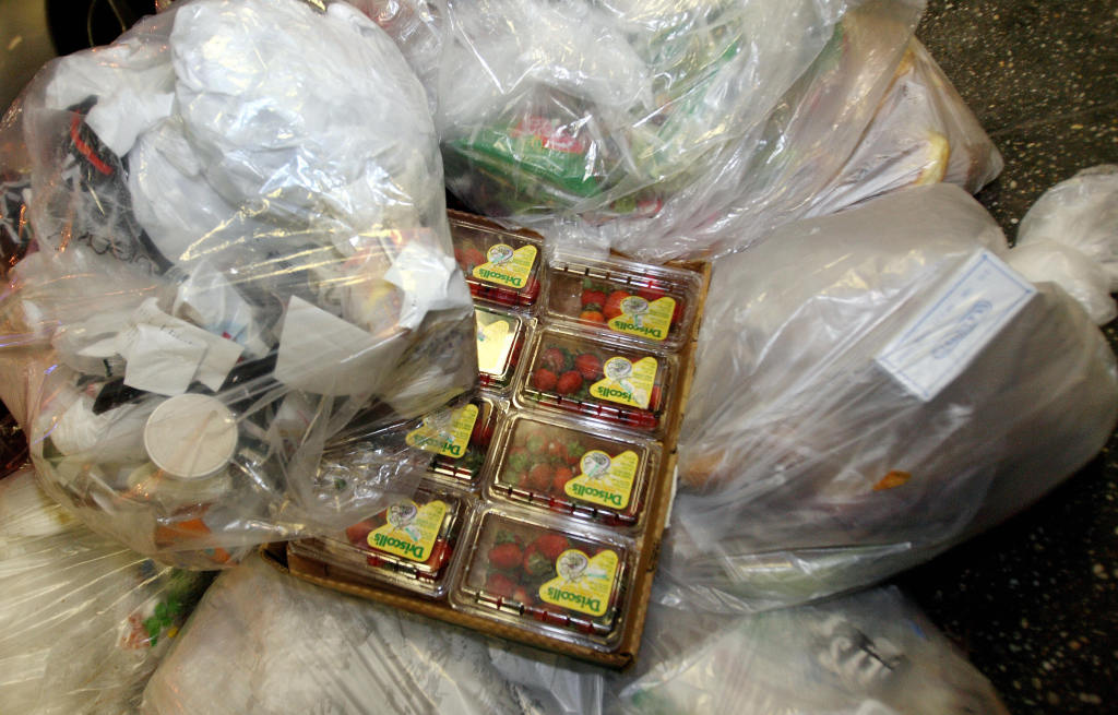 Boxes of strawberries sit amongst bags of trash found by "Freegans" outside of a grocery store in New York.  