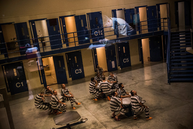 An officer is reflected in the glass as inmates sit in the county jail on July 26, 2013 in Williston, North Dakota.