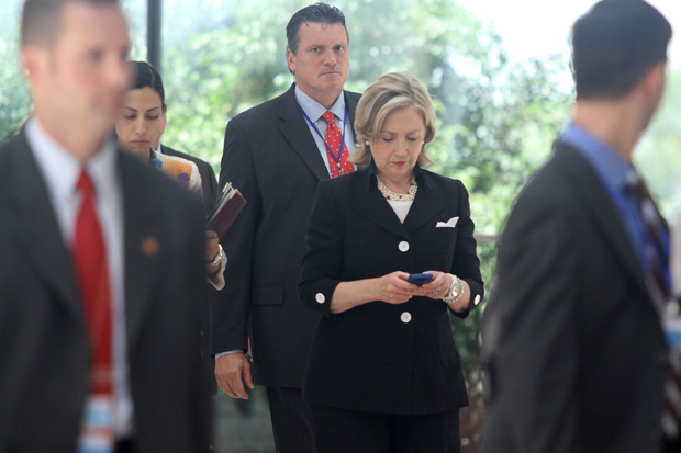 In this 2010 file photo, then-U.S. Secretary Of State Hillary Clinton (C) looks at her mobile phone after attending a meeting  in Hanoi.