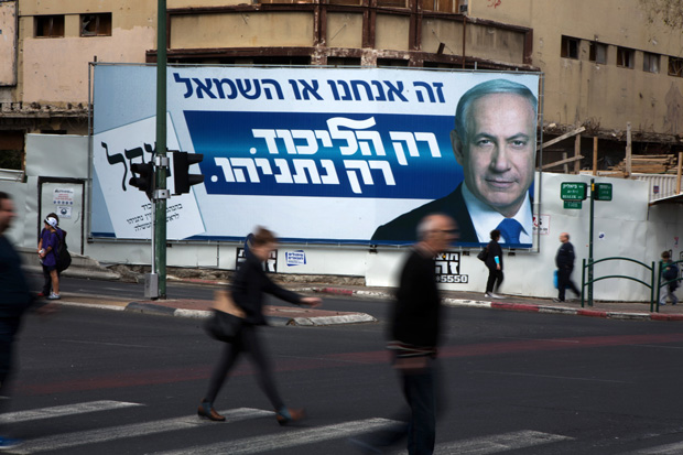 This March 12 photo shows Israelis in Ramat Gan walking by campaign posters showing Israeli Prime Minister Benjamin Netanyahu. Israelis vote March 17 in an election seen as a referendum on Netanyahu's tenure.
