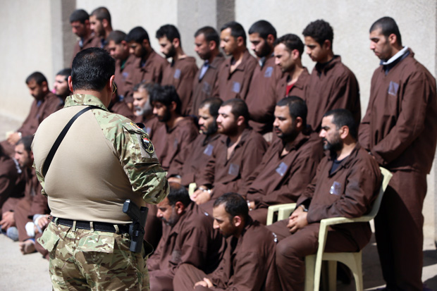 A member of Iraqi secruity forces (L) guards 31 suspected Islamic State group members at the Iraqi Intelligence service's headquarters in Baghdad on March 16, 2015.