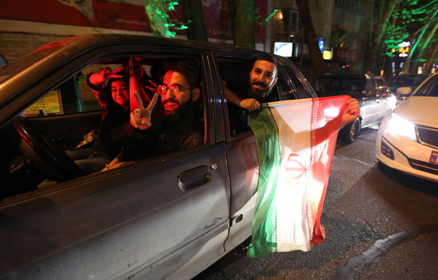People flash the "V for Victory" sign and hold an Iranian flag out of a car window April 2 as they celebrate on Valiasr street in northern Tehran after the announcement of an agreement on Iran nuclear talks.