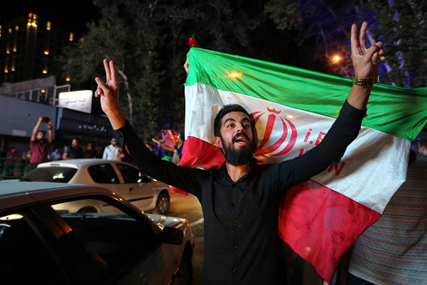 An Iranian man flashes the victory sign as an other holds the Iranian national flag during a celebration July 14 in northern Tehran after Iran's nuclear negotiating team struck a deal with world powers in Vienna. 