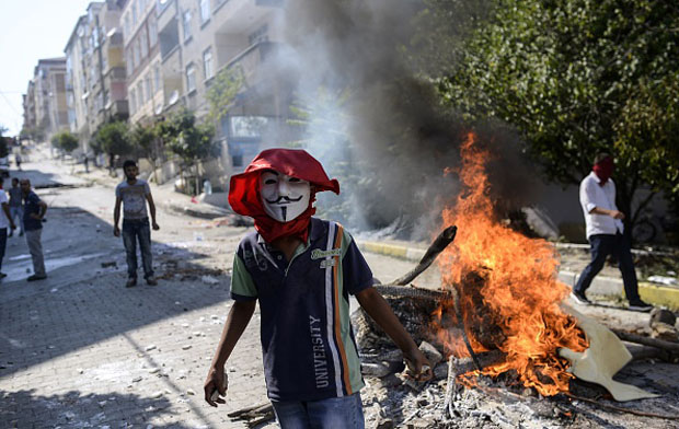 A left-wing militant wearing a "Guy Fawkes" mask stands by a burning barricade July 26 during clashes with Turkish riot police in Istanbul's Gazi district. 