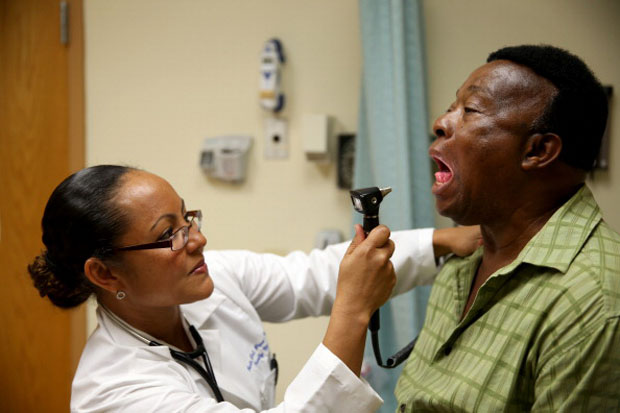 This 2014 file photo shows the newly-insured Felue Chang receiving a checkup from Dr. Peria Del Pino-White at the South Broward Community Health Services in Hollywood, Florida.