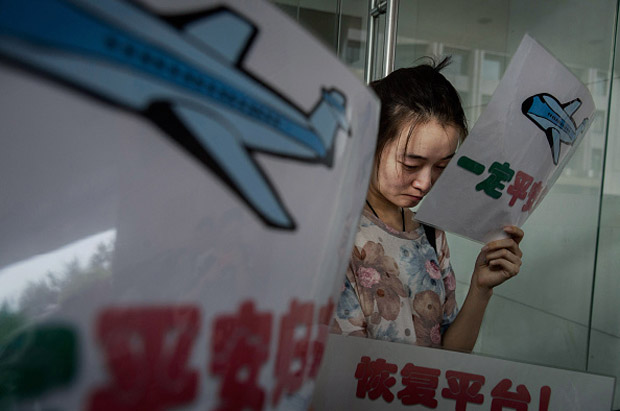 A Chinese relative of a missing passenger on Malaysia Airlines flight MH 370 weeps Aug. 6 as she and others wait for information outside the airline's office in Beijing, China. 