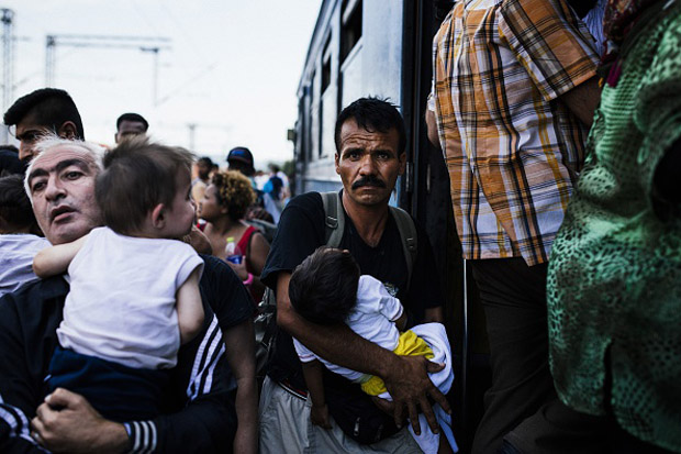 Men carry their children as migrants try to get on a train heading to the border with Serbia. Many migrants try to cross Macedonia and Serbia to enter the European Union via Hungary, a country that will finish building its anti-migrant fence on its border with Serbia by Aug. 31.