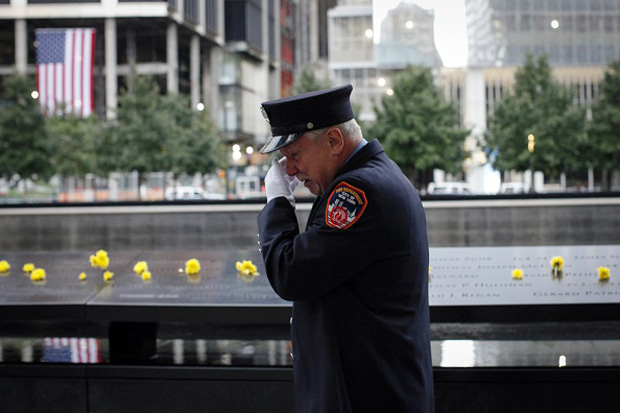 A member of the New York Fire Department reacts after he placed a flower on the 9/11 memorial on Sept. 11, 2015. 