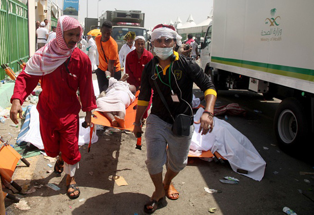 Saudi emergency personnel and Hajj pilgrims carry a wounded person at the site where at least 450 were killed and hundreds wounded in a stampede in Mina, near the holy city of Mecca.