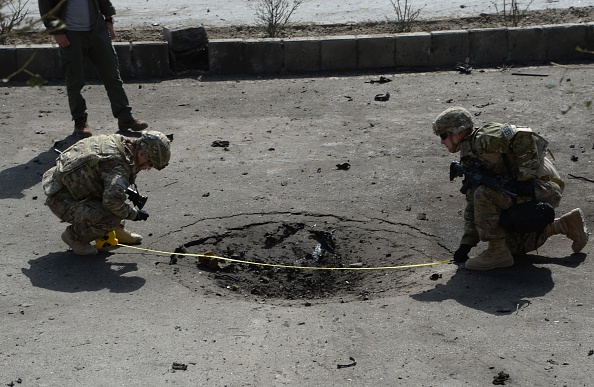 NATO soldiers measure a crater at the site of a suicide car bomb attack that targeted foreign military vehicles at Jo-e-Sher in Kabul, Afghanistan, on Oct. 11. President Obama said Thursday that the United States will keep thousands of troops in Afghanistan through the end of his term as president.