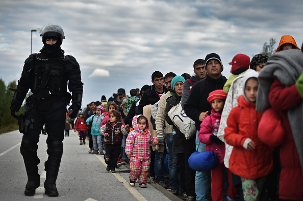 Migrants are escorted Thursday by police through Dobova, Slovenia, as they walk to a holding camp. Thousands of migrants marched across the border between Croatia into Slovenia as authorities intensify their efforts to attempt to cope with Europe's largest migration of people since World War II.
