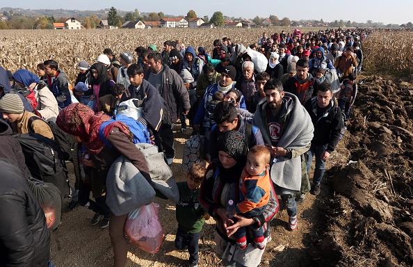 
Migrants and refugees who spent the night outdoors are escorted by Slovenian soldiers and police officers as they walk towards a refugee camp after crossing the Croatian-Slovenian border near Rigonce, Slovenia, on Monday.