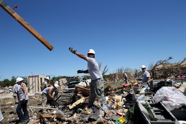 Workers with Team Rubicon sift through the remains of a home that was damaged by a tornado on June 2, 2013 in Moore, Oklahoma. Team Rubicon is an aid organization that unites military veterans with emergency first responders.