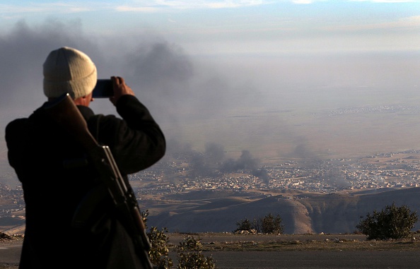 A displaced Iraqi man from the Yazidi community looks on as smoke billows during an operation by Iraqi Kurdish forces backed by U.S.-led strikes in the northern Iraqi town of Sinjar on Thursday. 