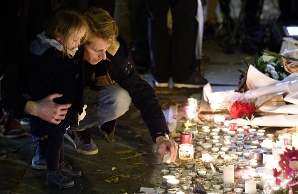A man puts a candle at a makeshift memorial near the Bataclan concert hall on Saturday in Paris.