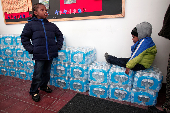 Justin Roberson, left, age 6, and Mychal Adams, age 1, of Flint, Michigan, wait on a stack of bottled water at a Jan. 17 rally where the Rev. Jesse Jackson was speaking about the city's water crisis. 