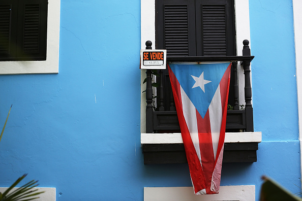 A for sale sign is seen hanging from a balcony next to a Puerto Rican flag in San Juan, Puerto Rico in July 2015.