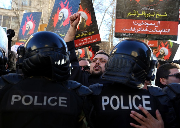 Iranian protesters hold portraits of prominent Shiite Muslim cleric Nimr al-Nimr as they confront riot police Sunday during a demonstration against his execution by Saudi authorities. Saudi Arabia severed ties with Iran as tensions between the two countries escalated.