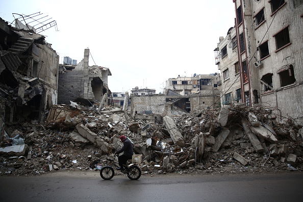 A man rides a bicycle past the rubble of a destroyed building in the rebel-held town of Douma, on the eastern edges of the Syrian capital Damascus, on January 5.