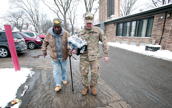 A member of the Michigan National Guard helps a Flint, Michigan, resident take bottled water out to his car after he received it at a fire station on Wednesday. Michigan's governor activited the National Guard in response to lead contamination in the city's water supply.