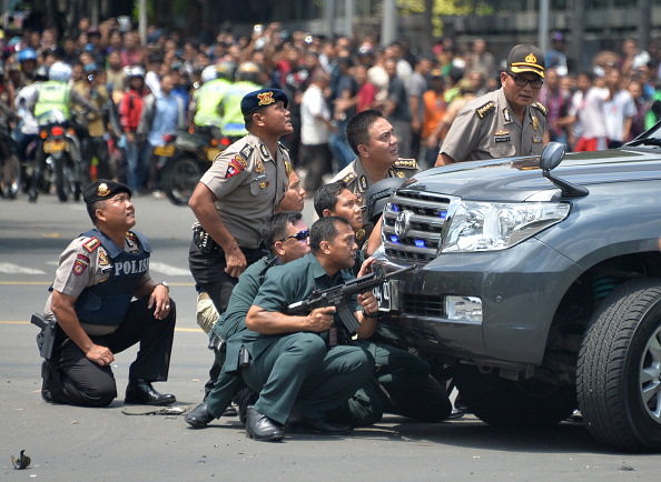 Indonesian police take position behind a vehicle as they pursue suspects after a series of blasts hit the Indonesia capital Jakarta on Thursday.
