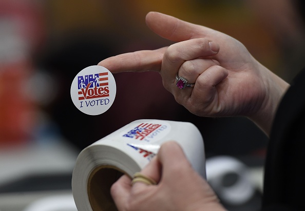 An election worker hands out stickers to voters after casting their ballots at Belmont High School February 9 in Belmont, New Hampshire.