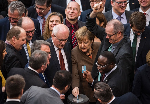 German Chancellor Angela Merkel (C) and deputies vote on a migrant bill at the Bundestag, the country's lower house of parliament, in Berlin on February 25.