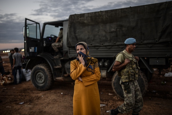A Syrian Kurdish woman stands in front of military truck after crossing the border between Syria and Turkey after several mortars hit both sides near the southeastern town of Suruc in Sanliurfa province on September 29, 2014.