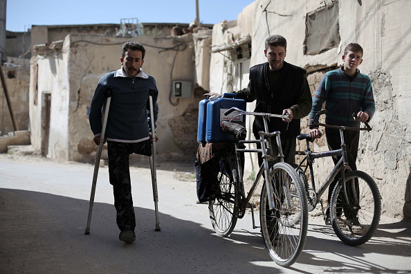 Syrians carry aid, in the form of diesel fuel, delivered by the Qatari Red Crescent in the rebel-held town of Beit Sawa, on the outskirts of the capital Damascus on March 7.