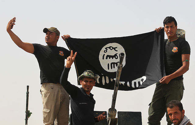 Shiite fighters from the Popular Mobilization units hold an Islamic State (IS) group upside down June 4 in the village of al-Azraqiyah as they advance towards a village north west of Fallujah during an operation to regain territory.