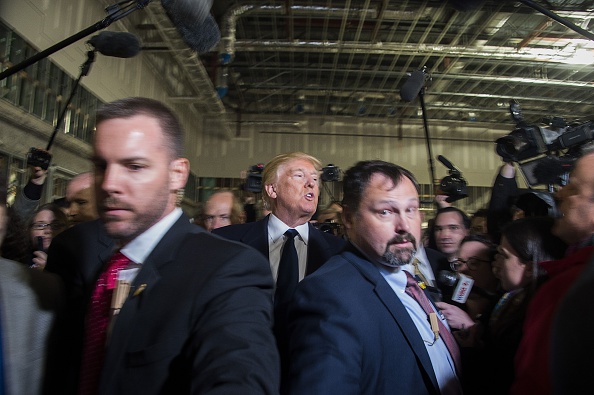 Republican presidential nominee Donald Trump (C) speaks with reporters as he tours the ball room construction at the Trump International Hotel in Washington, DC on March 21.