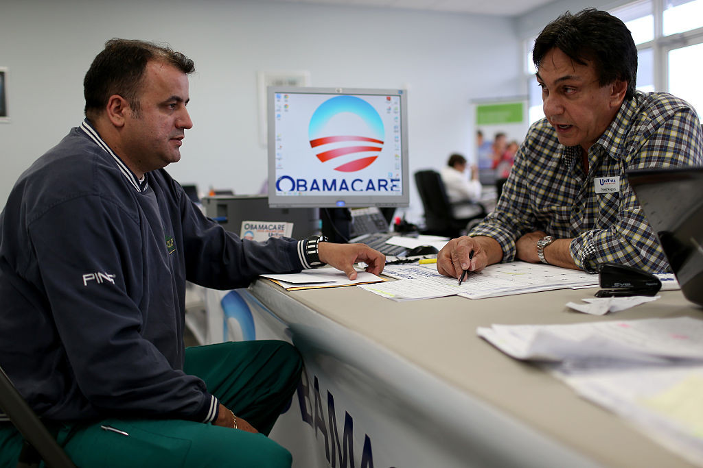 Ariel Fernandez (L) sits with Noel Nogues, an insurance  advisor with UniVista Insurance company, as he signs up for the Affordable Care Act, also known as Obamacare, before the February 15th deadline on February 5, 2015 in Miami, Florida.