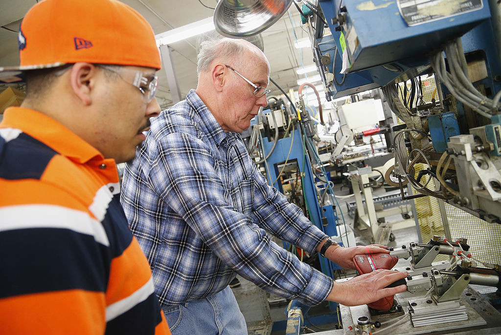 Employees Mark Fisher and Michael Bess stamp a football with the opponents' names for the Super Bowl at the Wilson Sporting Goods football factory on January 19, 2014 in Ada, Ohio.