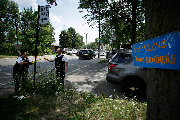Chicago Police officers hang yellow crime scene tape where a man was shot multiple times as he sat in a vehicle July 27 in Chicago, Illinois.