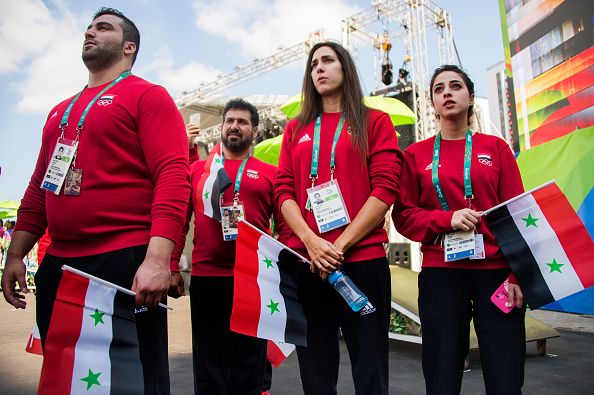 Syrian weightlifter Man Asaad (L), Syrian swimmer Baean Jouma (2nd R) and Syrian Women's Table Tennis Heba Allejji (R) stand for their national anthem during a welcoming ceremony at the Olympic Village ahead of the Rio 2016 Olympic Games in Rio de Janeiro, on August 4.
