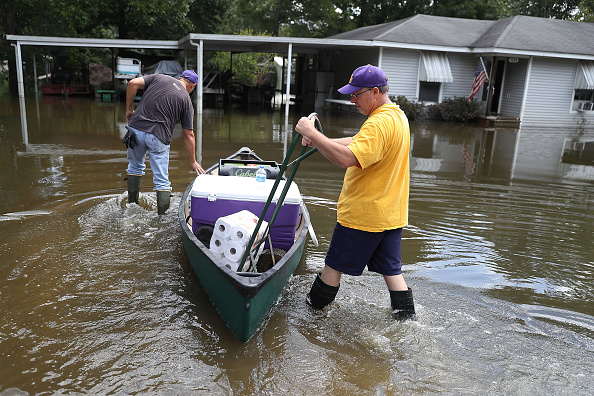 Mike Sittig (L) and Nelson Morgan, Jr. bring supplies to Nelson's father's home to begin the process of cleaning up after flood waters inundated it on August 19 in St. Amant, Louisiana.
