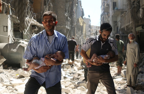 Syrian men carrying babies make their way through the rubble of destroyed buildings following a reported air strike on the rebel-held Salihin neighbourhood of the northern city of Aleppo on September 11.
 AFP / AMEER ALHALBI        (Photo credit should read )