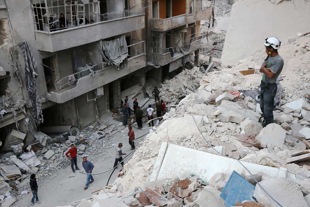 A Syrian civil defense volunteer stands on the rubble of destroyed buildings during a rescue operation following a government forces air strike on the rebel-held neighbourhood of Bustan al-Basha in the northern city of Aleppo, on October 4, 2016.