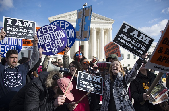 Pro-choice and pro-life activists mingle as they hold up placards and chant in front of the U.S. Supreme Court in Washington, D.C.