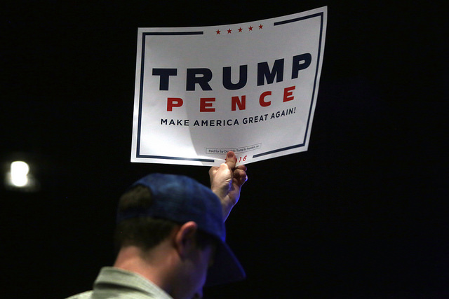 A man holds a sign supporting Donald Trump and Mike Pence at a 2016 campaign rally and church service at the Living Word Bible Church in Mesa, Arizona.