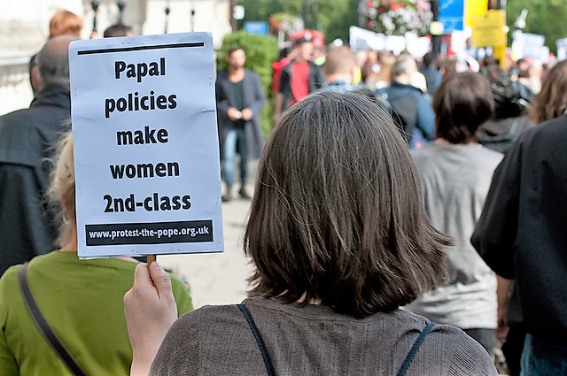 A woman holds a sign at a protest in London. 
