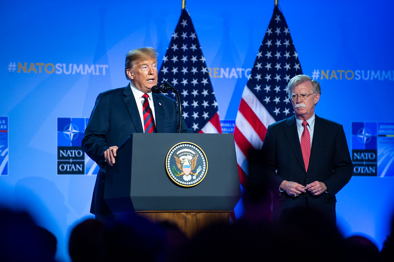 Former national security adviser John Bolton stands beside President Trump at a NATO summit in Brussels in 2018.
