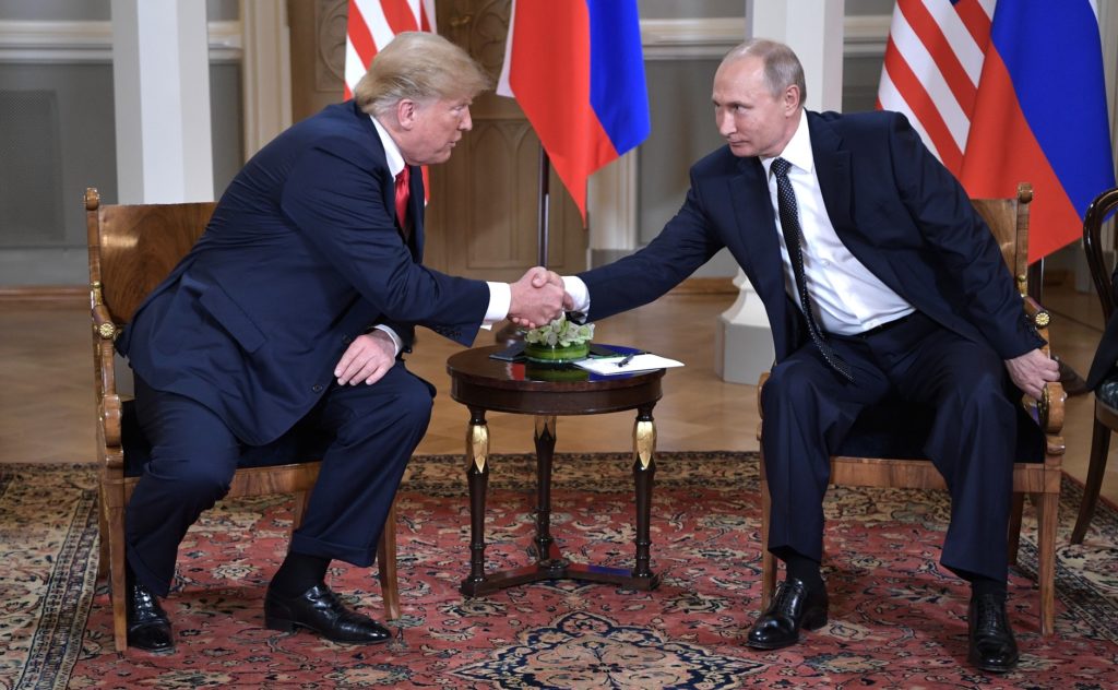 Donald Trump and Vladimir Putin shake hands at a summit in Helsinki in July 2018. A new report by the Senate Intelligence Committee details interactions between Russian government operatives and members of Trump's 2016 campaign staff. 