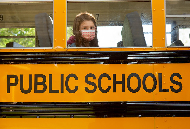 An elementary student waits for her bus to leave school after dismissal.