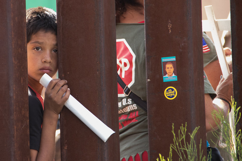 A boy stands at the border wall in Nogales, Arizona, during a 2017 protest against U.S. border policies under President Trump. Joe Biden has promised a very different approach to immigration, moving forward with reforms, even as border officials struggle to process a new surge of unaccompanied minors.