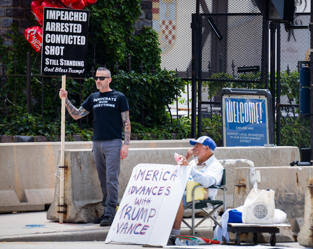 Supporters of Donald Trump hold up signs outside the entrance of the 2024 Republican National Convention.